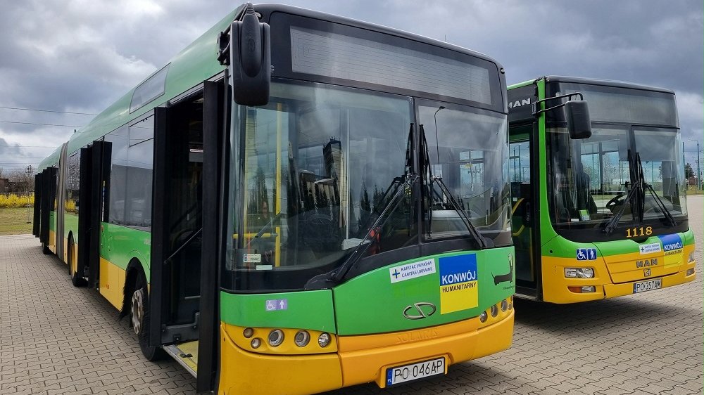 Dwa autobusy zielono-żółte autobusy MPK z naklejkami na maskach "Konwój humanitarny"