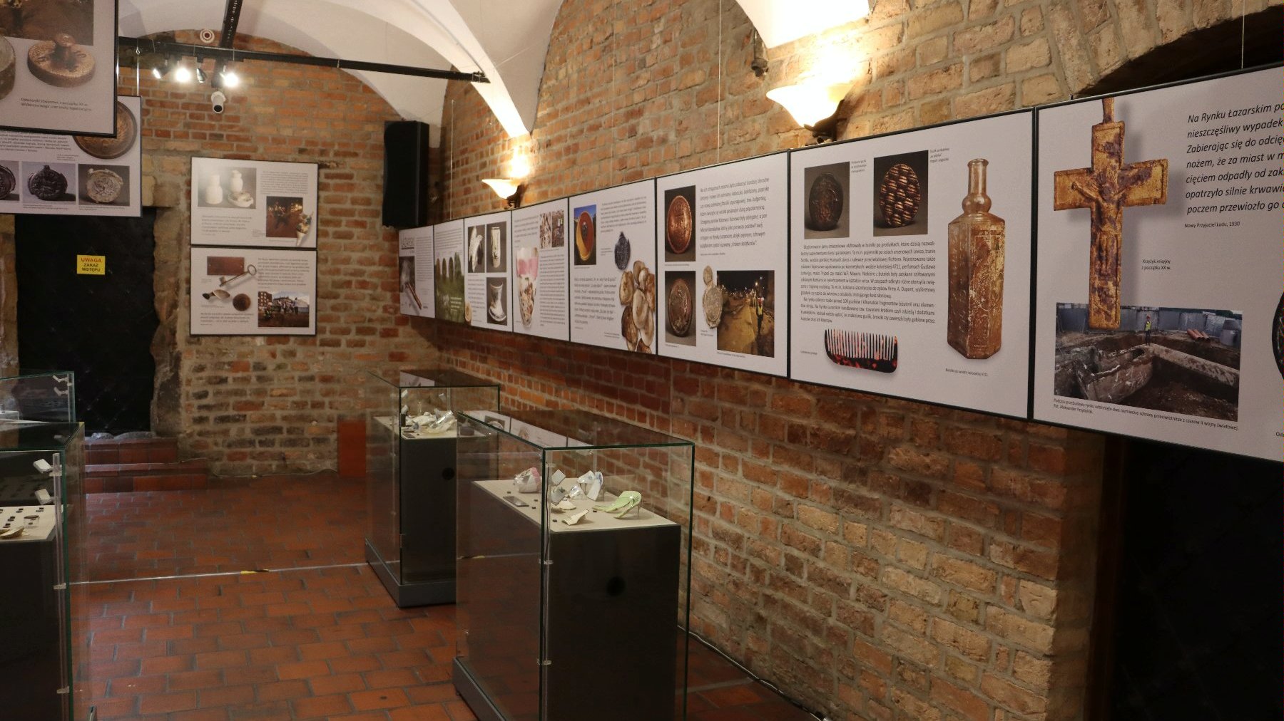 sala z gablotami i eksponatami, na ścianie tablice informacyjne ze zdjęciami i opisami historycznymi