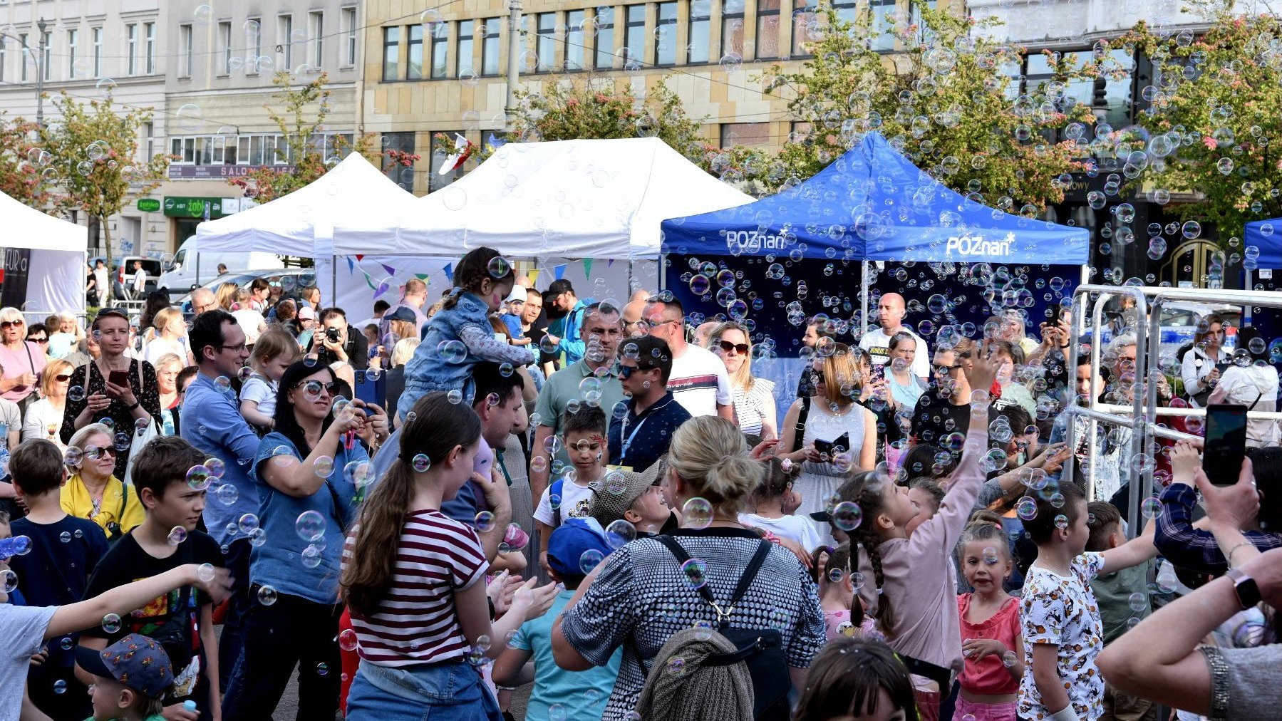 Na zdjęciu tłum ludzi, parasole, unoszące się w powietrzu bańki mydlane