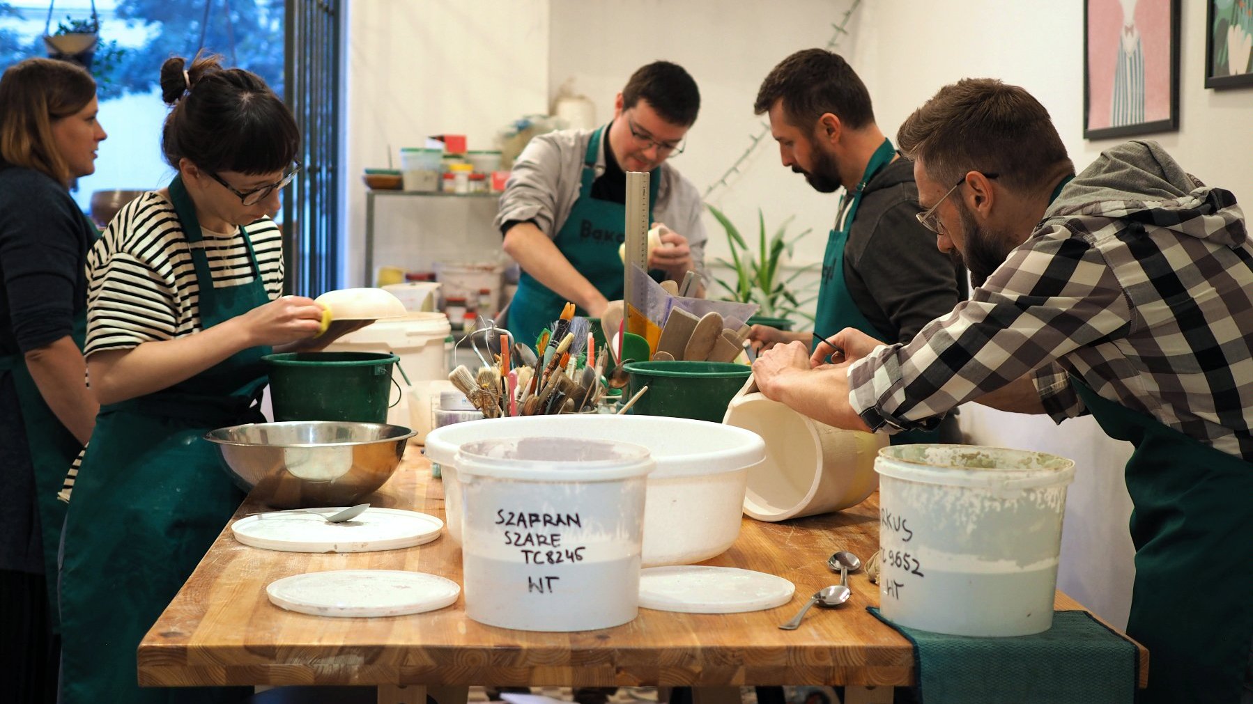 Grupa ludzi przy stole wytwarzająca naczynia ceramiczne