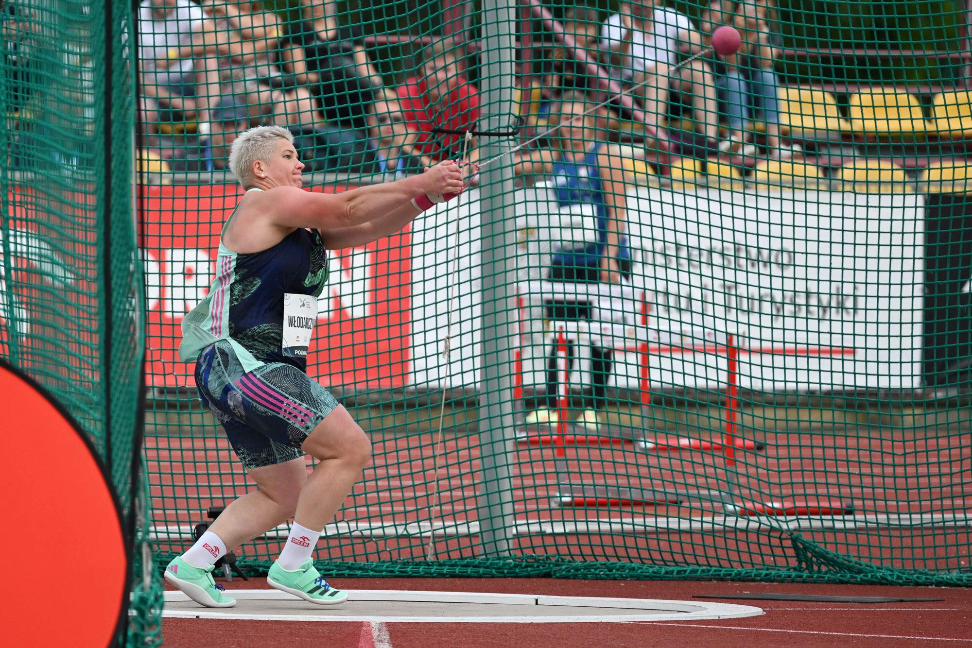 Zdjęcie przedstawia Anitę Włodarczyk wykonującą rzut młotem podczas zawodów sportowych