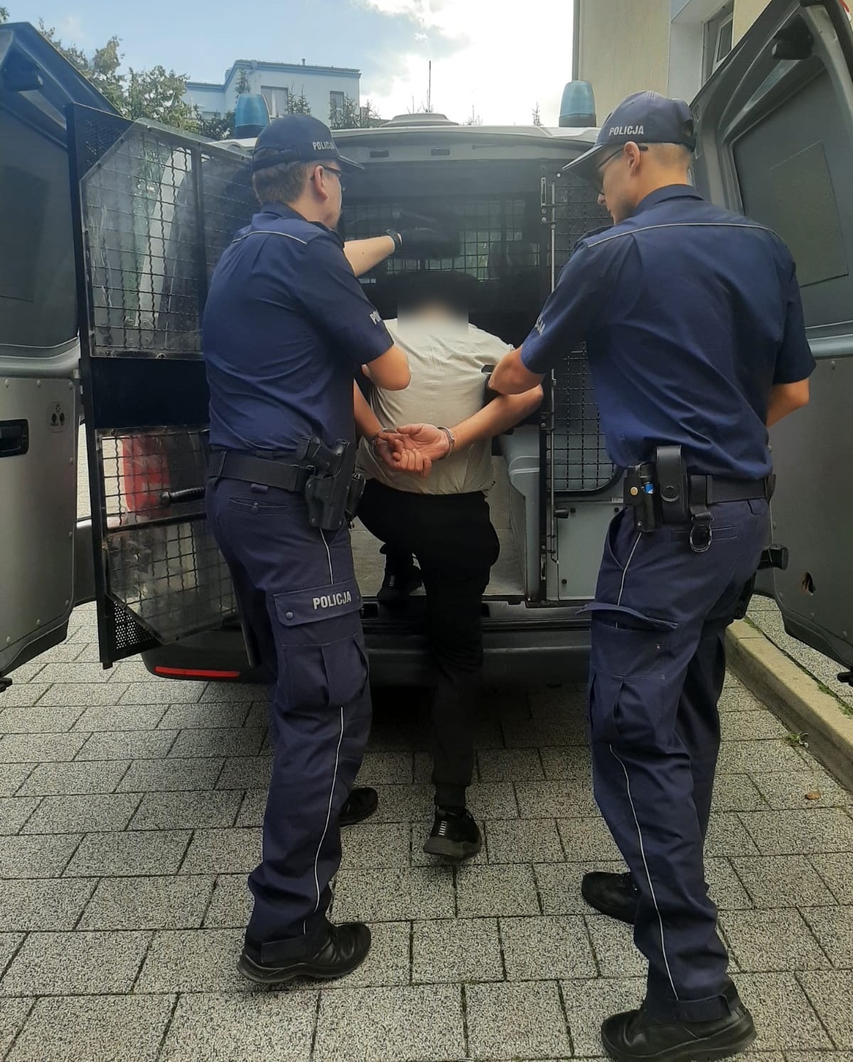 Dwóch funkcjonariuszy policji aresztuje mężczyznę.