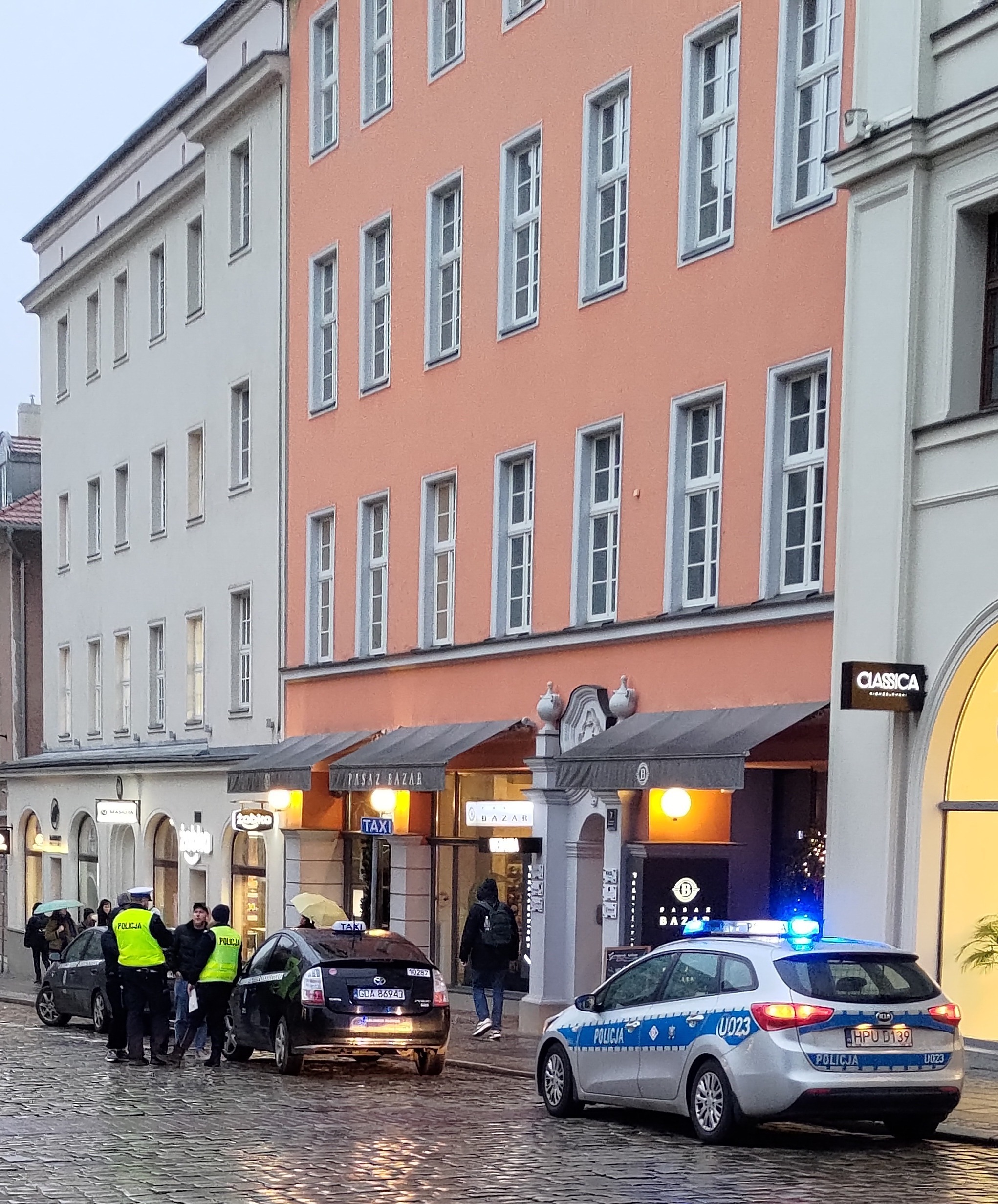 Interwencja policji na ulicy Paderewskiego. Dwóch funkcjonariuszy rozmawia z kierowcą taksówki.